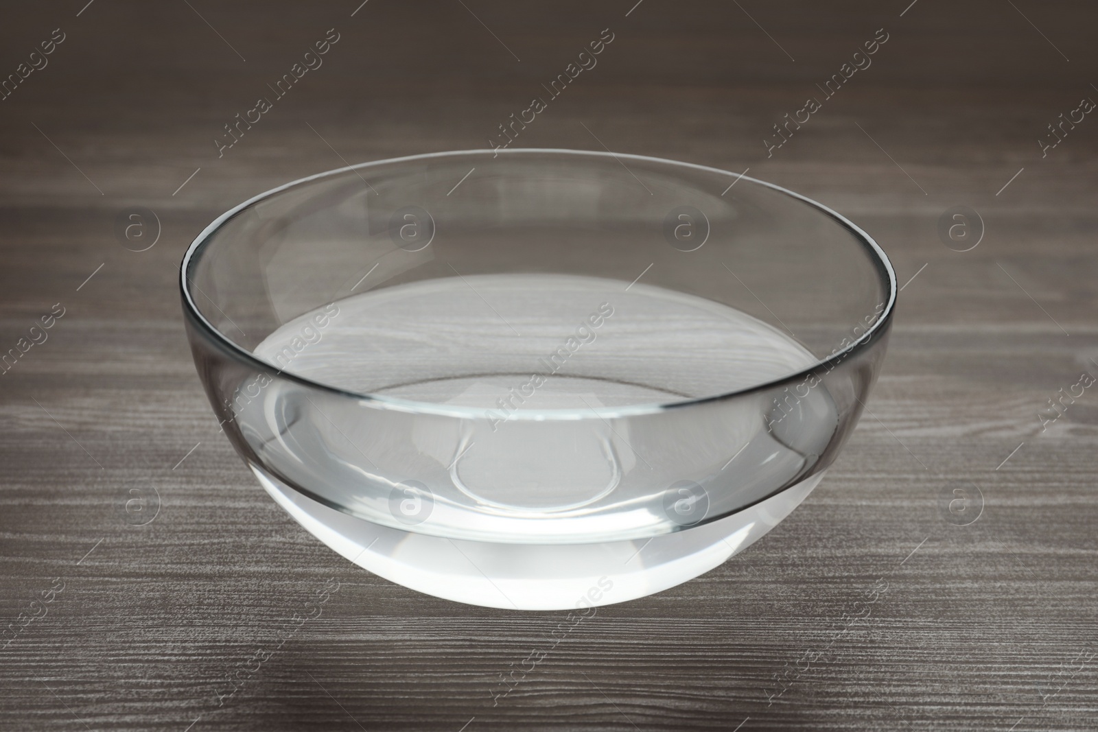Photo of Glass bowl with water on dark wooden table