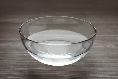 Glass bowl with water on dark wooden table
