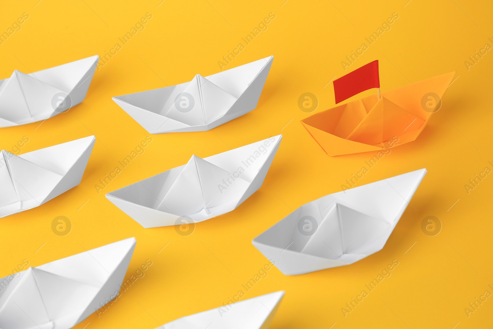 Photo of Group of paper boats following yellow one on color background. Leadership concept