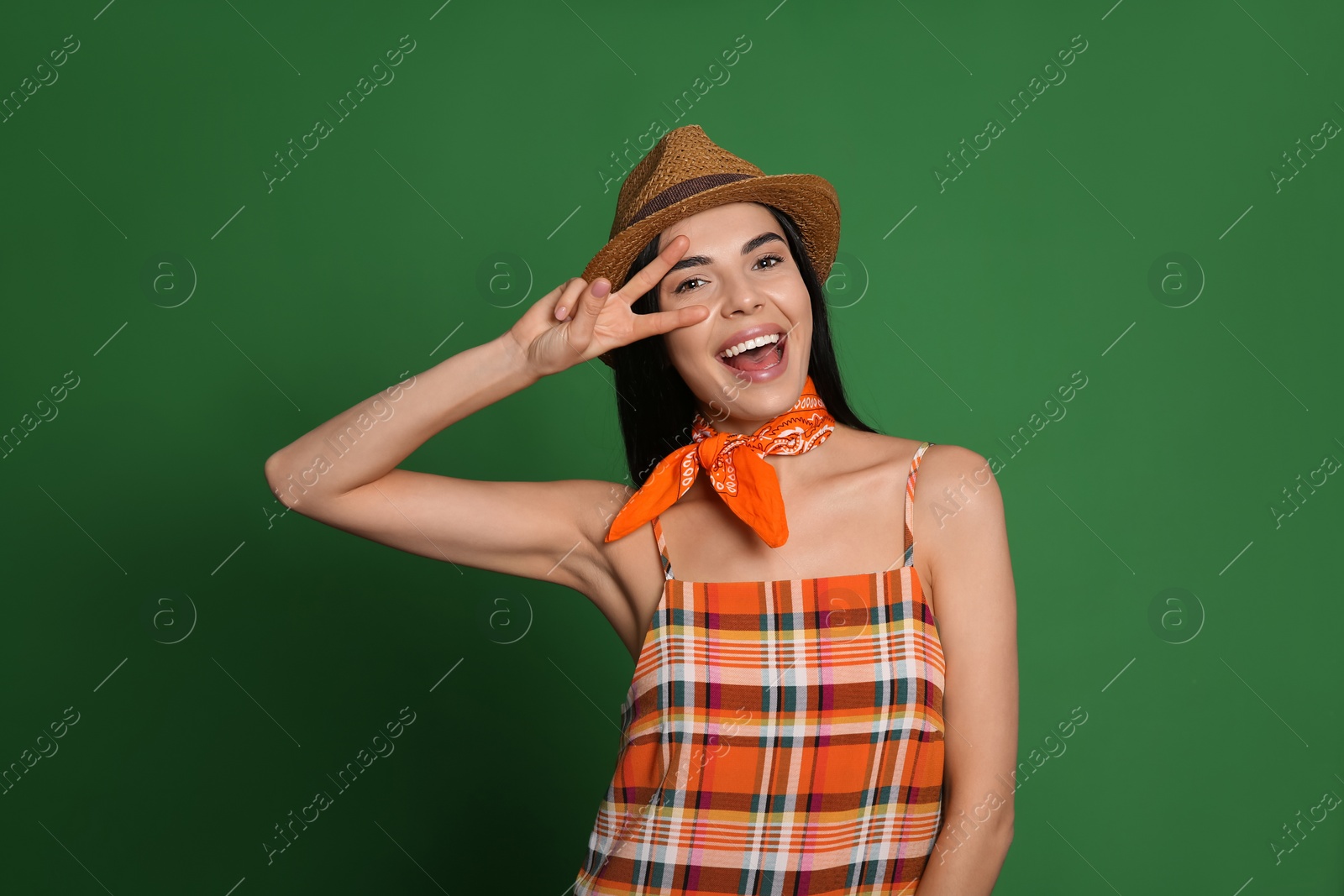 Photo of Fashionable young woman in stylish outfit with bandana on green background