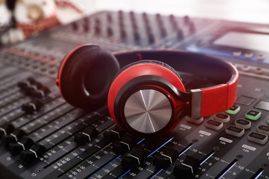 Photo of Headphones on professional mixing console in modern radio studio, closeup