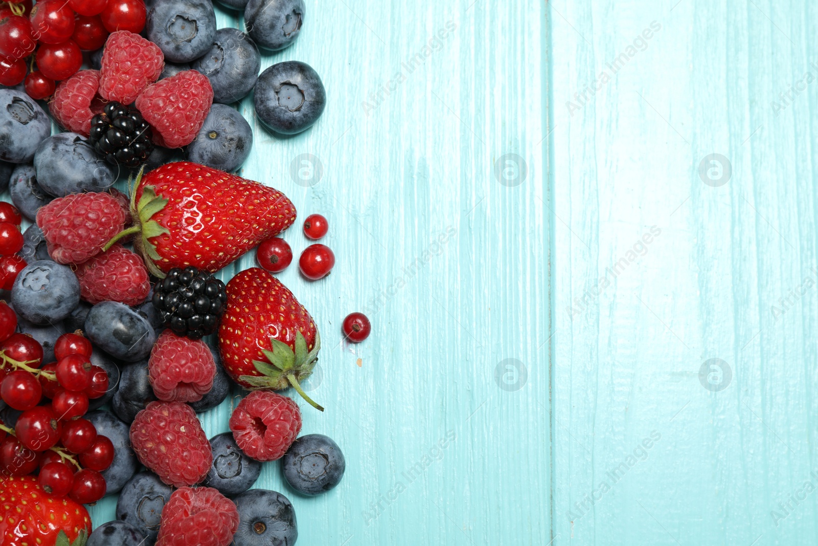 Photo of Different fresh berries on light blue table, flat lay. Space for text