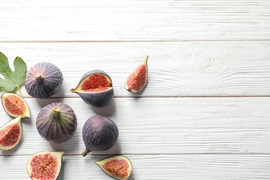 Photo of Flat lay composition with whole and cut purple figs and space for text on wooden background