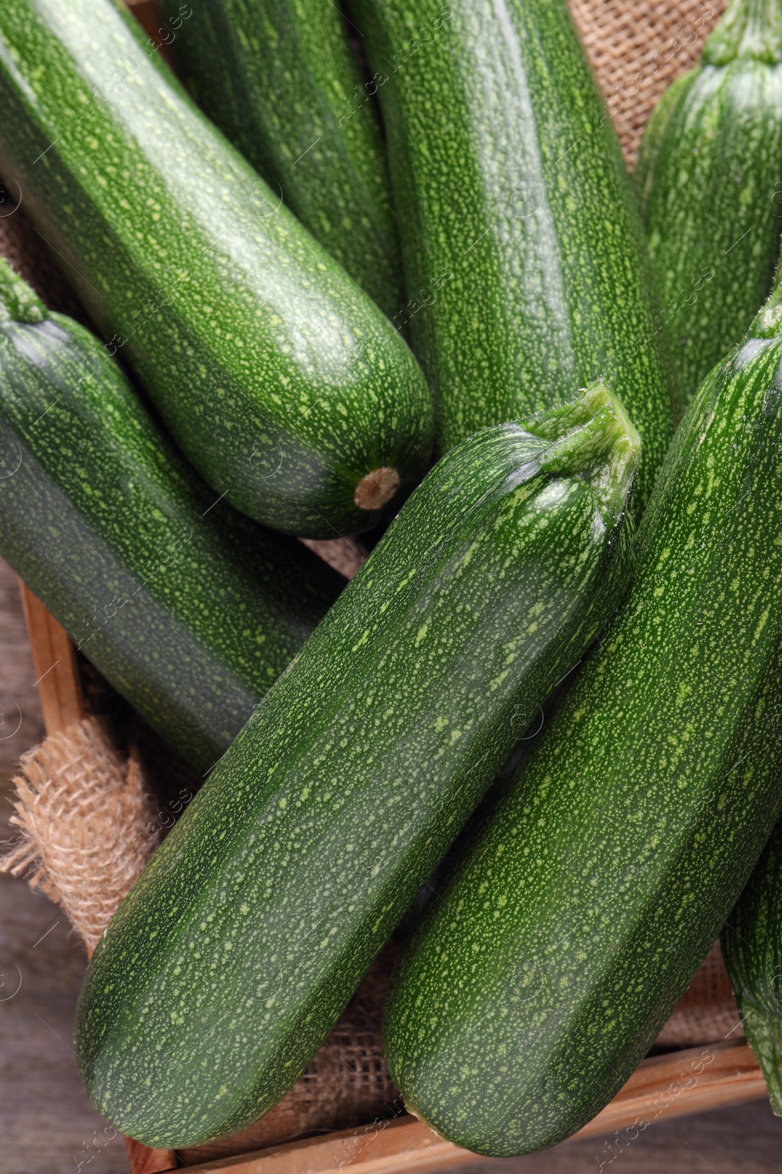 Photo of Raw ripe zucchinis in wooden crate, closeup