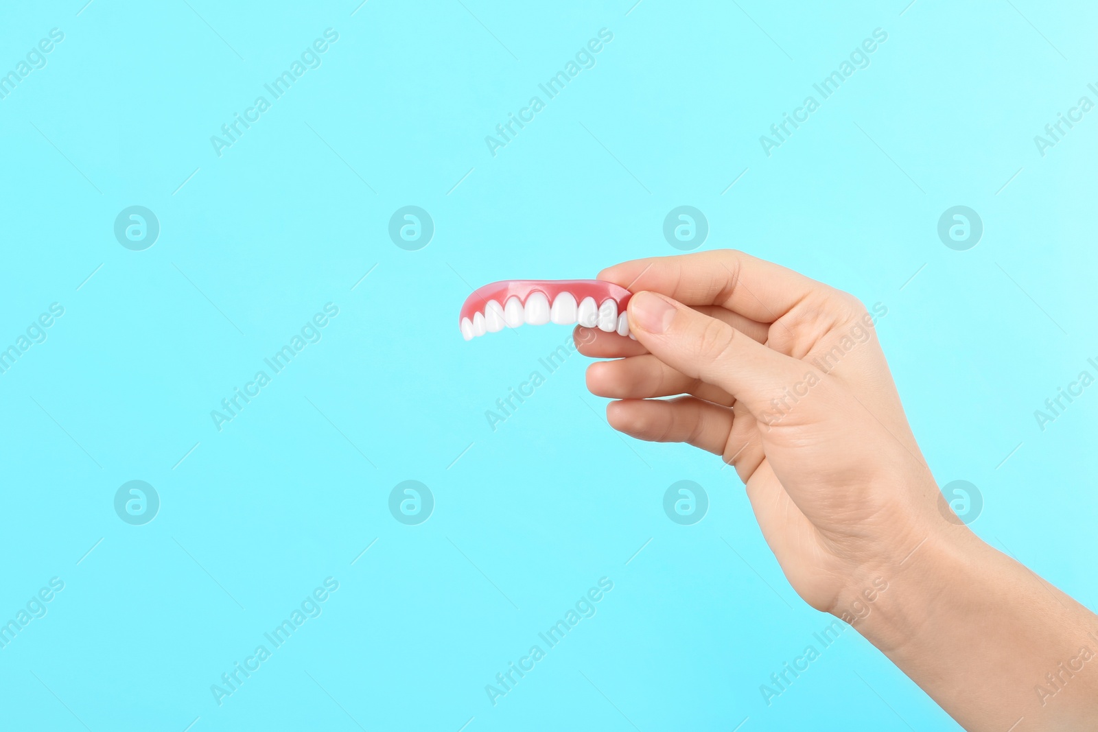 Photo of Woman holding teeth cover on color background. Space for text