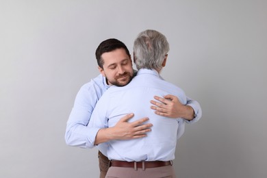 Photo of Happy son and his dad hugging on gray background