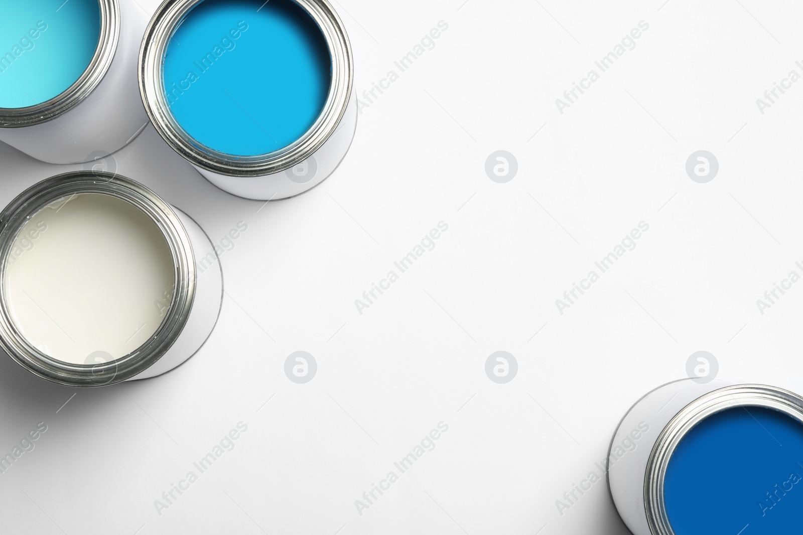 Photo of Open paint cans on white background, top view. Space for text