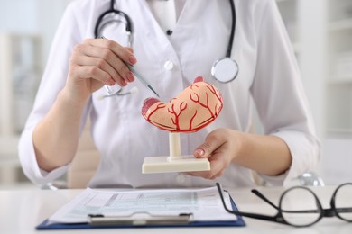 Photo of Gastroenterologist showing human stomach model at table in clinic, closeup