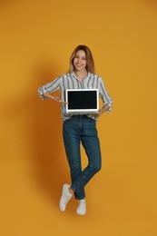 Photo of Young woman with modern laptop on yellow background