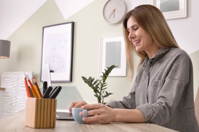 Young woman working with laptop at desk in home office