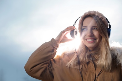 Young woman with headphones listening to music outdoors. Space for text