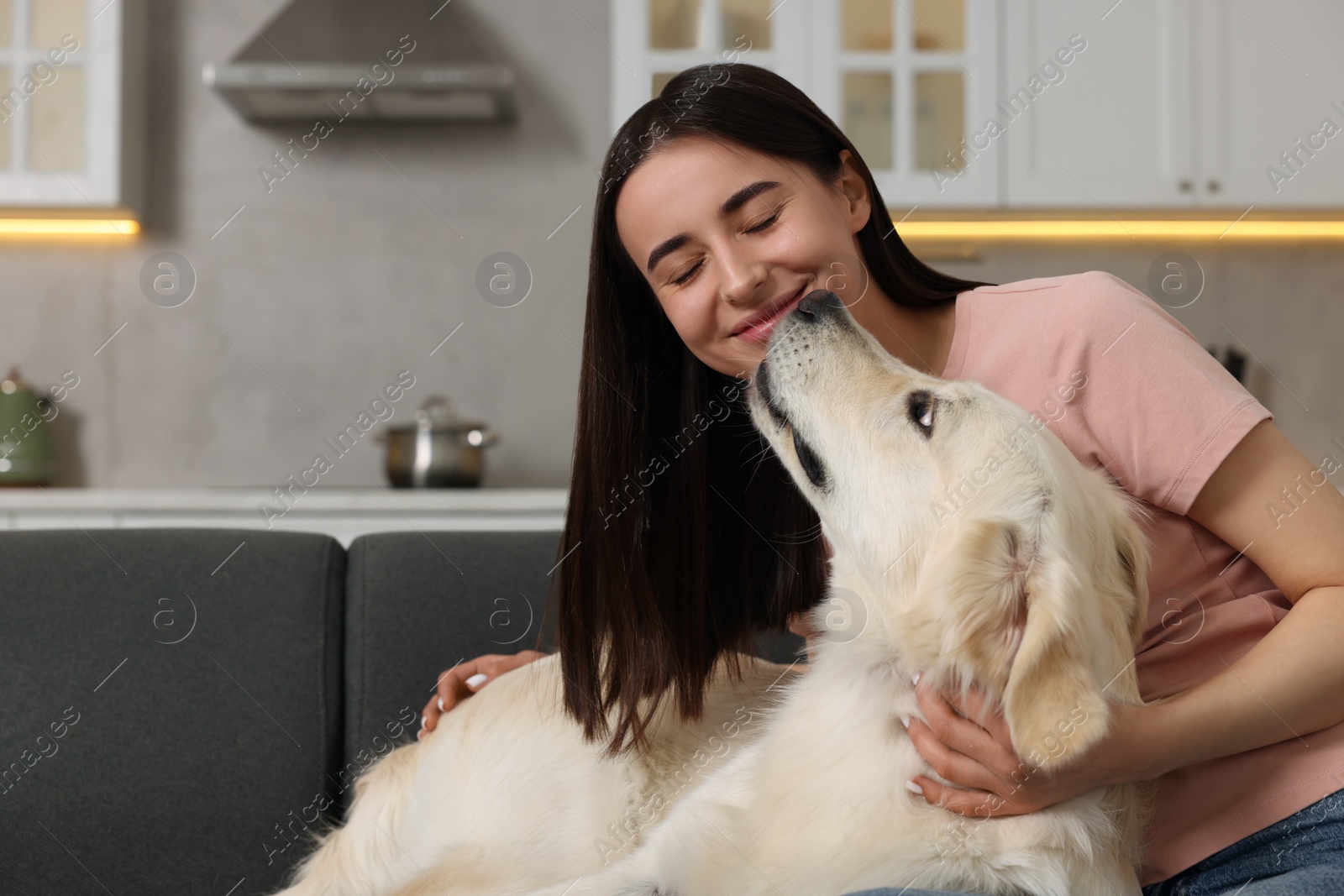 Photo of Happy woman with cute Labrador Retriever dog on sofa at home. Adorable pet