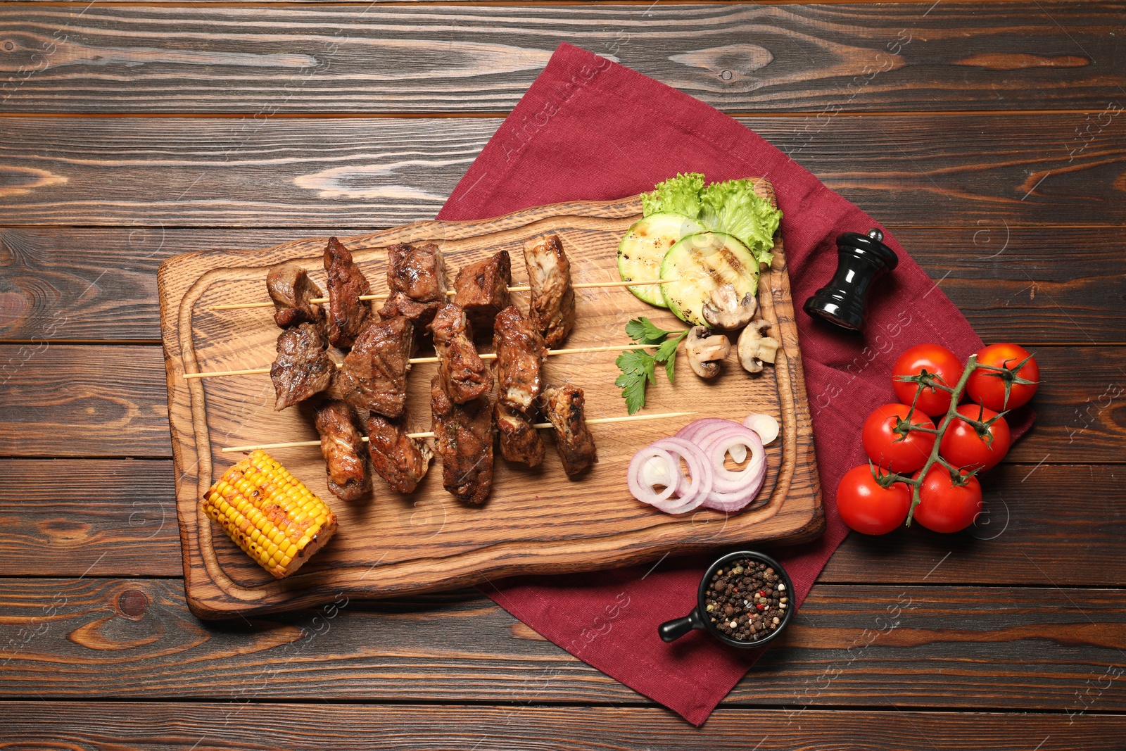 Photo of Delicious shish kebabs with vegetables and spices on wooden table, flat lay