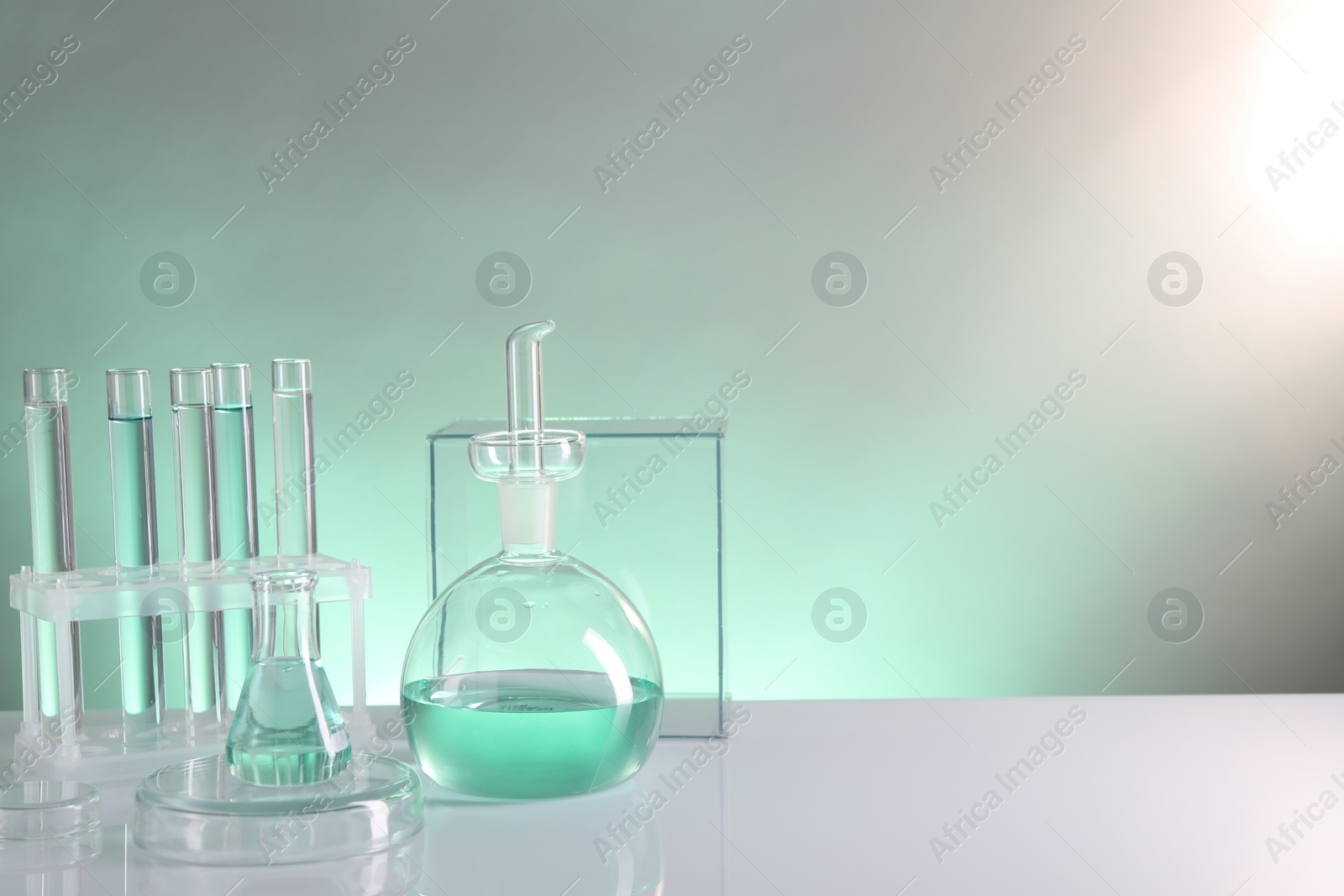 Photo of Laboratory analysis. Different glassware on table against color background, space for text