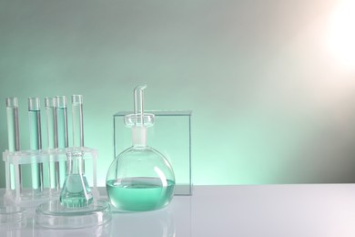 Photo of Laboratory analysis. Different glassware on table against color background, space for text