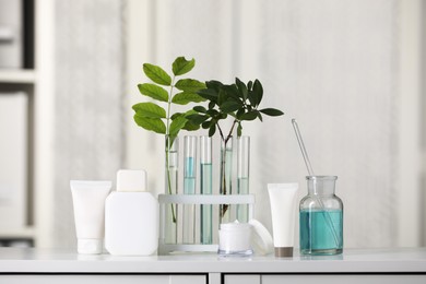 Photo of Many containers and glass tubes with leaves on white lab drawer indoors