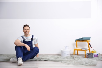 Photo of Young male decorator on floor in room