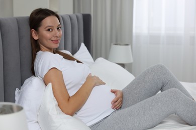 Photo of Beautiful pregnant woman with long hair in bedroom