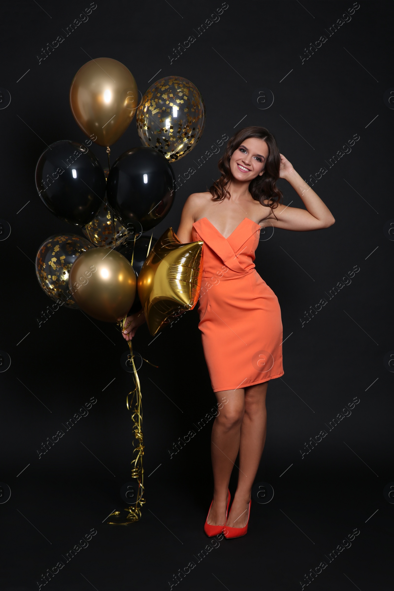 Photo of Happy woman with air balloons on black background. Christmas party