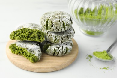 Board with stacked tasty matcha cookies and powder on white table, closeup