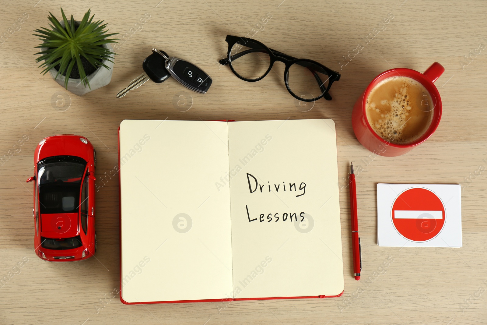 Photo of Flat lay composition with workbook for driving lessons and cup of coffee on white wooden background. Passing license exam