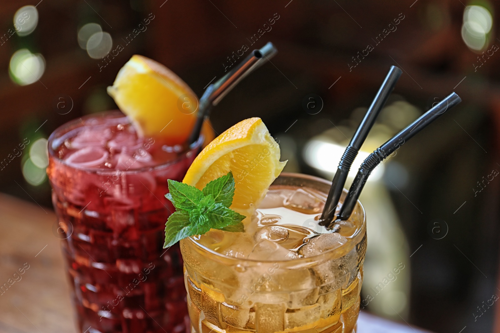 Photo of Glasses of delicious cocktails with ice on blurred background, closeup