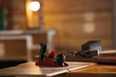 Photo of Hand plane and wooden plank on table in carpenter's workshop. Space for text