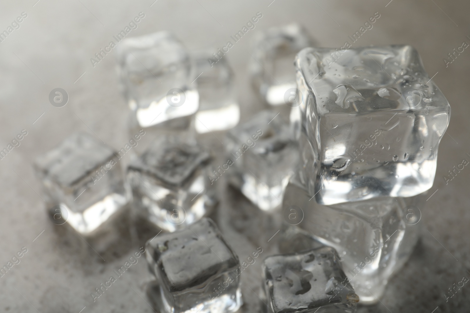 Photo of Crystal clear ice cubes with water drops on grey table, closeup