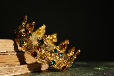 Photo of Beautiful golden crown and old books on black background. Fantasy item