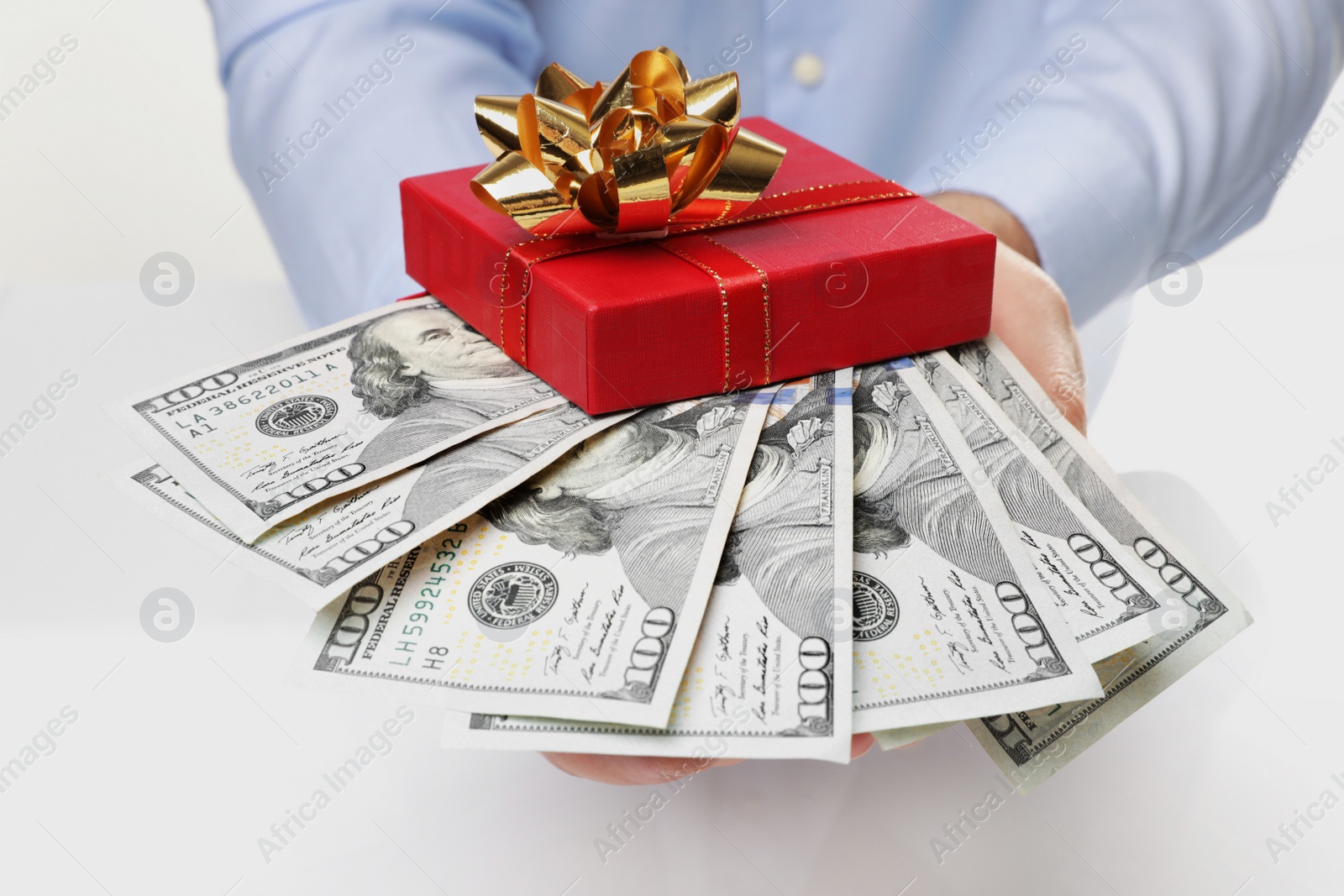 Photo of Man holding gift box with dollar banknotes on white background, closeup