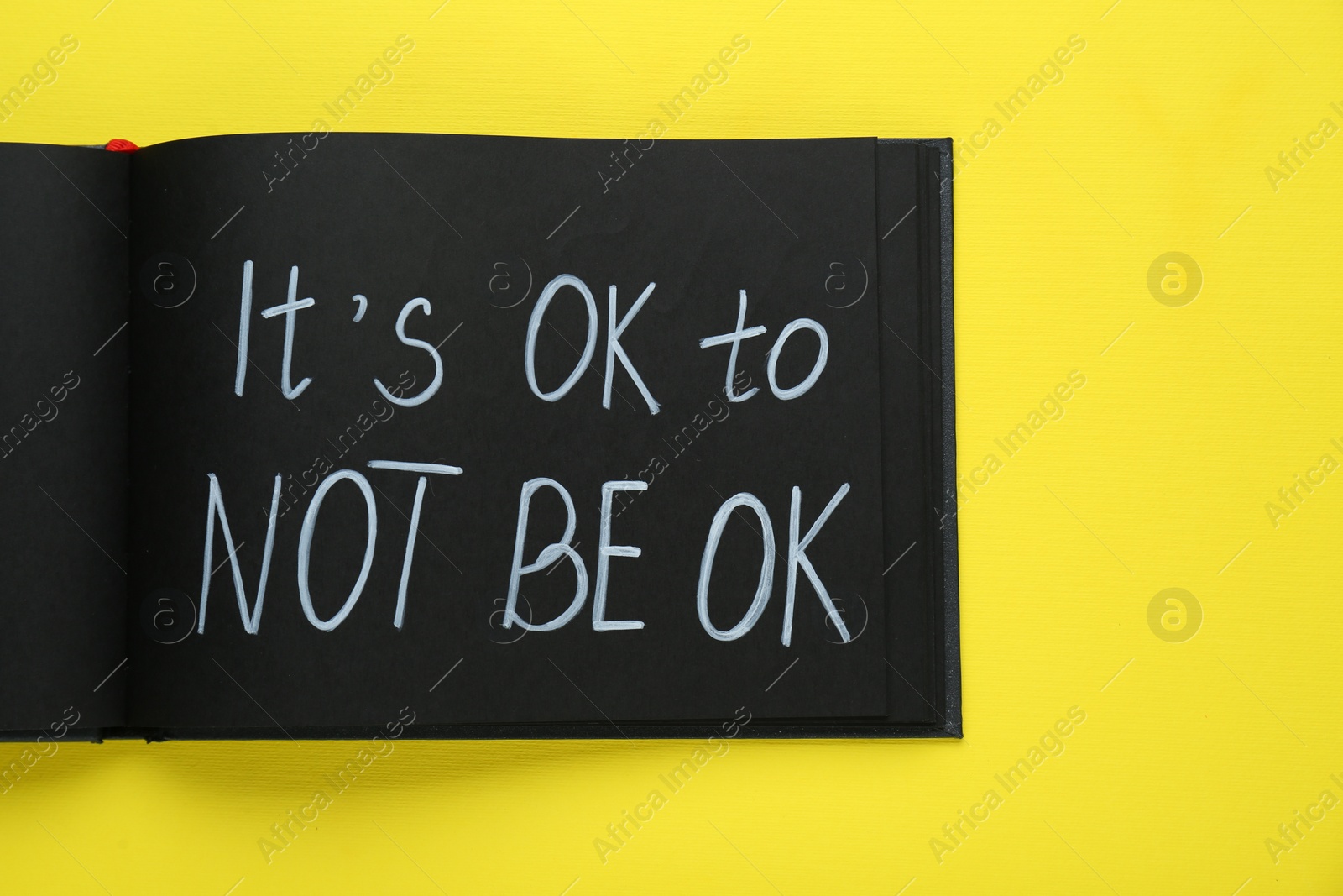 Photo of Notebook with phrase It`s Ok To Not Be Ok on yellow background, top view