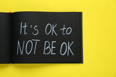 Photo of Notebook with phrase It`s Ok To Not Be Ok on yellow background, top view