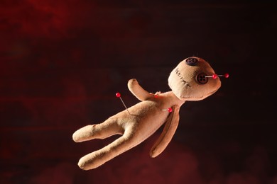 Photo of Voodoo doll with pins on dark red background