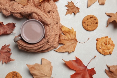 Flat lay composition with hot cozy drink and autumn leaves on light background