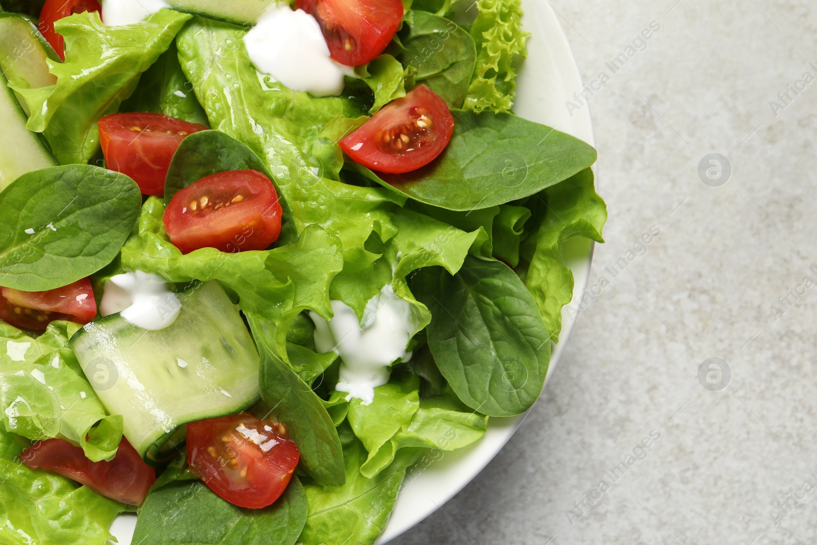 Photo of Delicious vegetable salad on light grey table, top view. Space for text