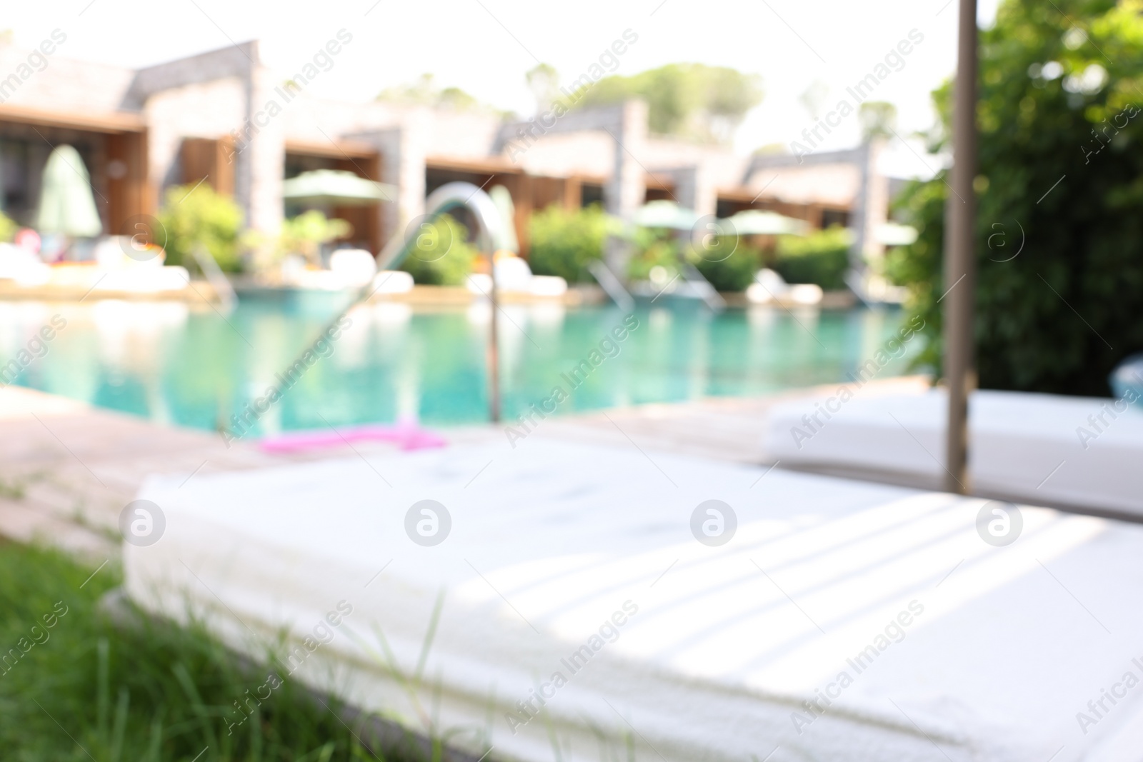 Photo of Sun loungers near outdoor swimming pool, blurred view. Luxury resort