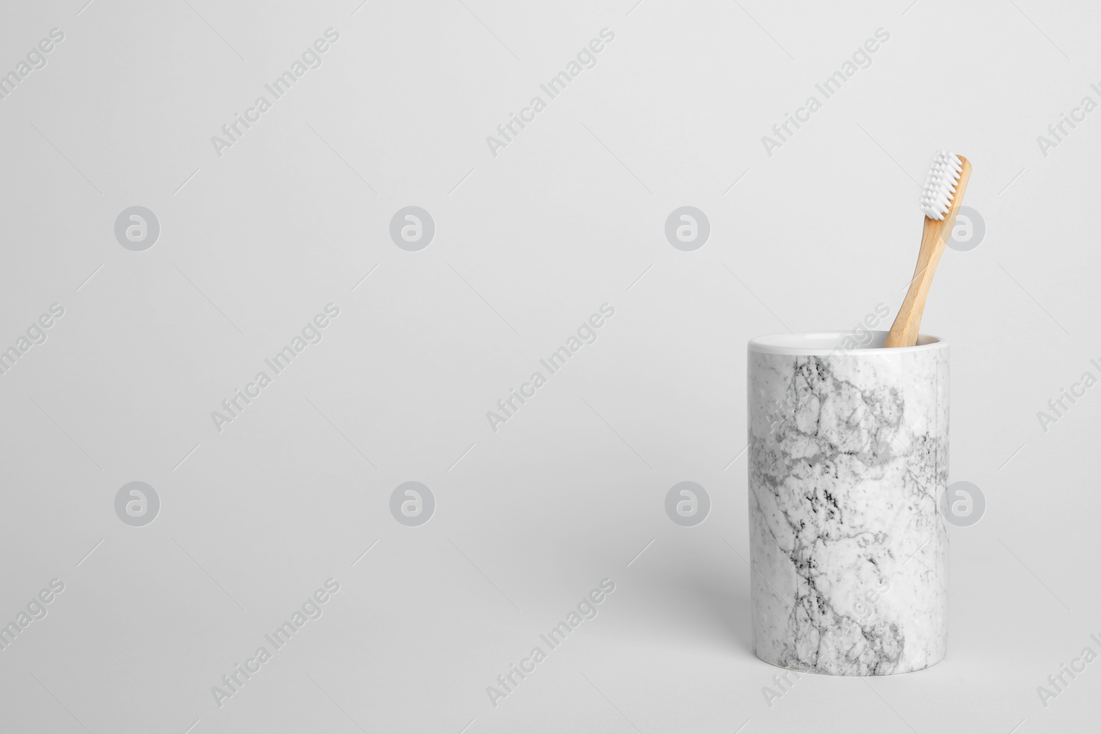 Photo of Bamboo toothbrush in holder on light background. Space for text