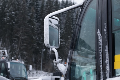 Photo of Vehicle side view mirror covered with hoarfrost and snow outdoors