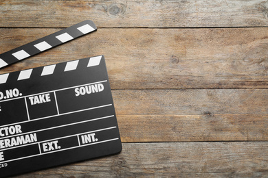 Clapperboard on wooden table, top view with space for text. Cinema production