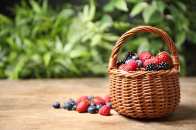 Photo of Mix of ripe berries on wooden table. Space for text