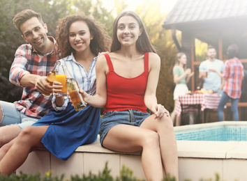 Image of Happy friends with drinks at barbecue party near swimming pool outdoors