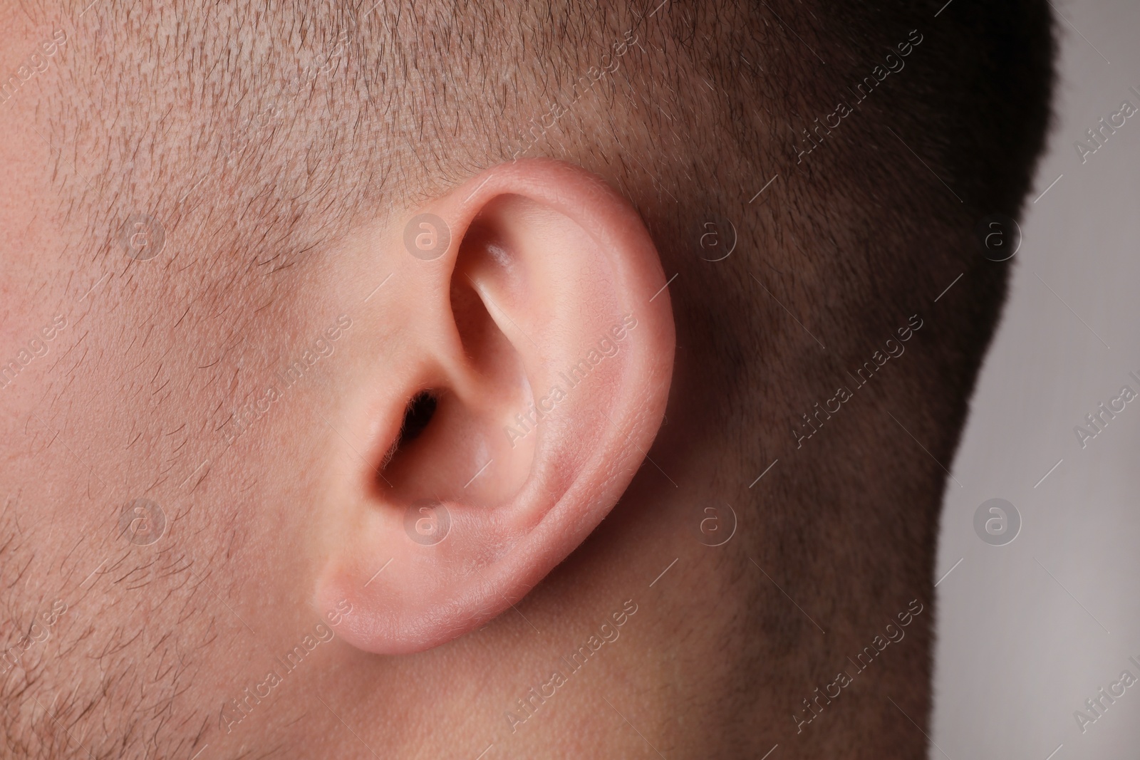 Photo of Man on grey background, closeup of ear