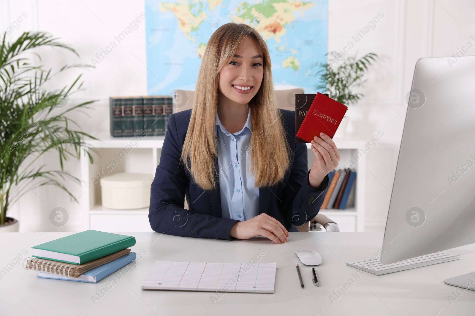 Photo of Happy manager holding passports at desk in travel agency
