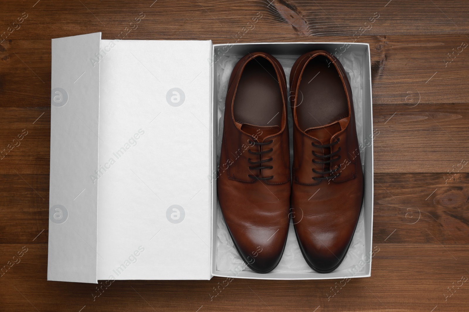 Photo of Pair of stylish leather shoes in white box on wooden background, top view
