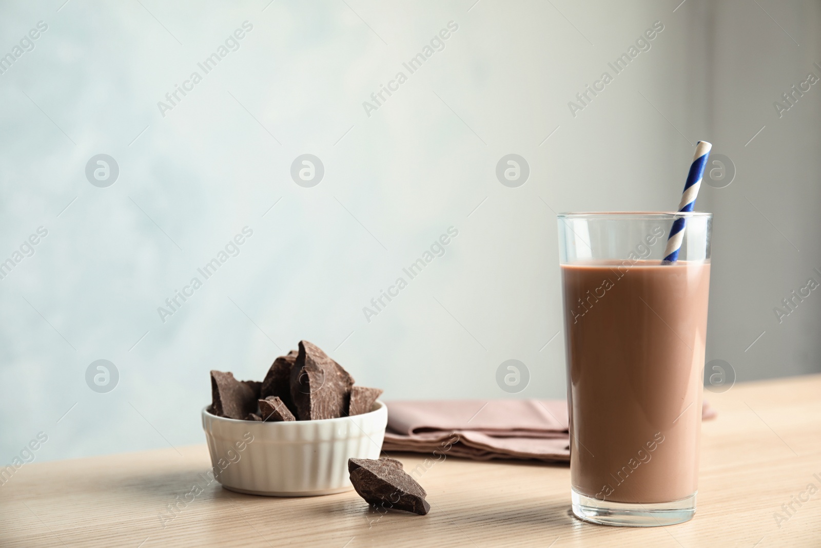 Photo of Glass of tasty chocolate milk on wooden table, space for text. Dairy drink