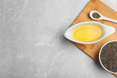 Composition with chia seeds and sauce boat of oil on grey table, top view. Space for text