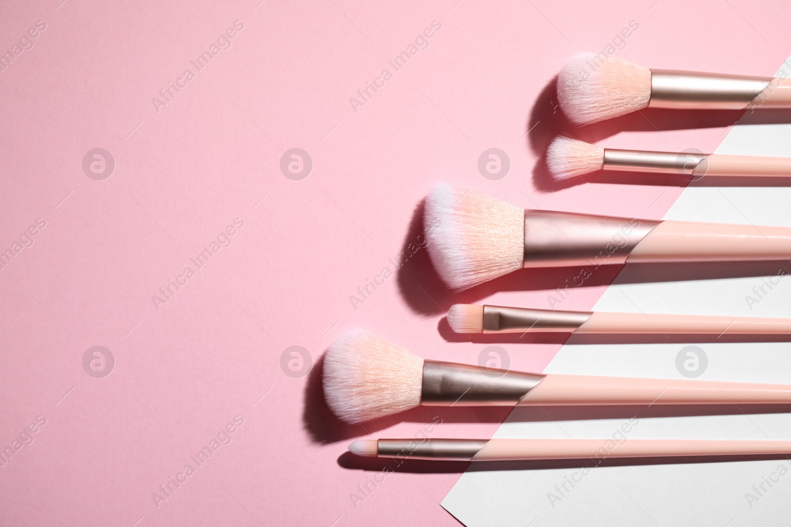 Photo of Flat lay composition with professional makeup brushes on color background. Space for text