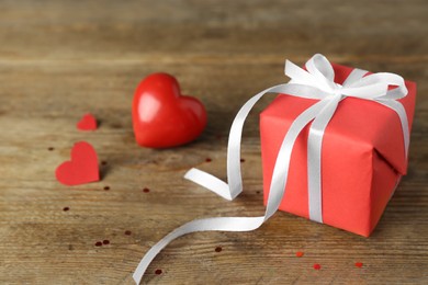 Photo of Beautiful gift box with red hearts on wooden table, closeup