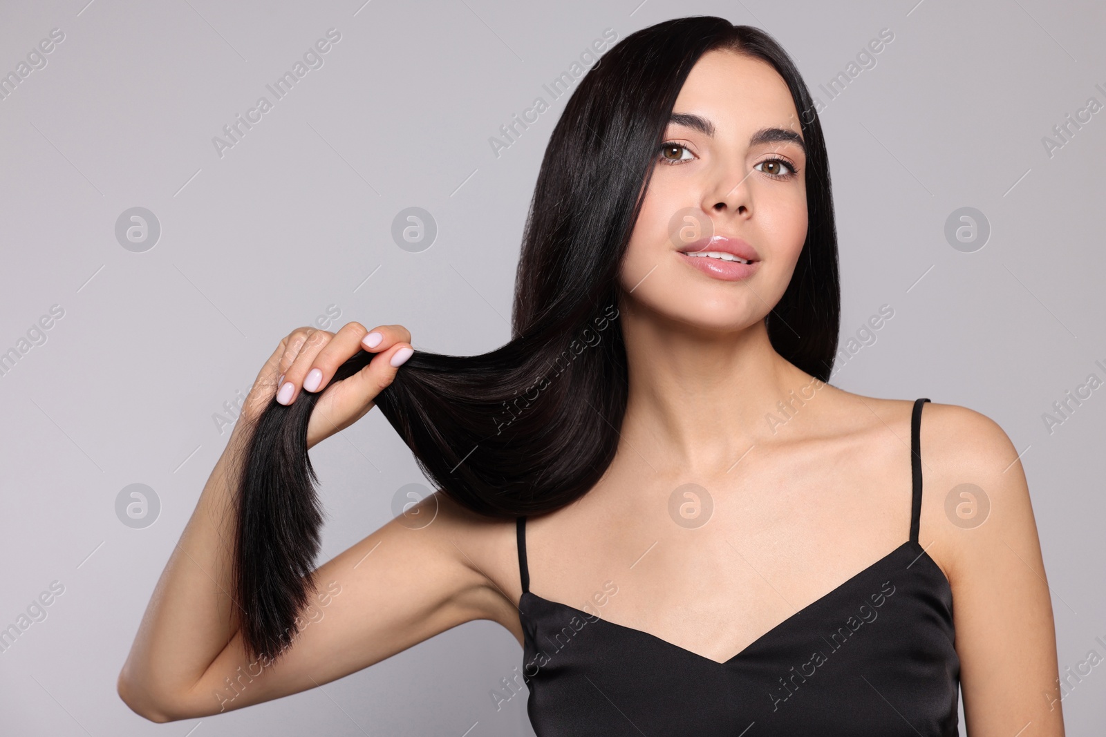Photo of Portrait of beautiful young woman with healthy strong hair on light grey background