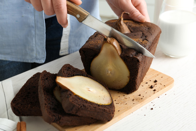 Photo of Woman cutting tasty pear bread at table, closeup. Homemade cake